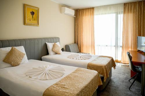 a hotel room with two beds and a desk at Paradise Hotel & Relax Center in Pomorie