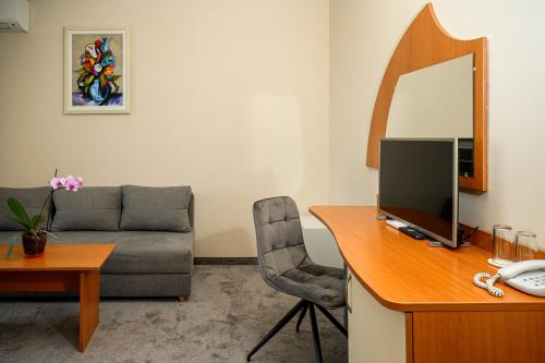 a living room with a desk with a computer and a couch at Paradise Hotel & Relax Center in Pomorie