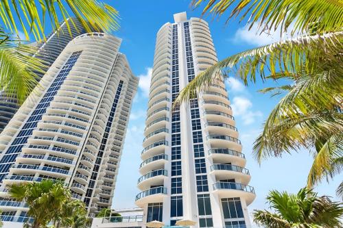 two tall condos on the beach with palm trees at Luxury Penthouse Oasis - Oceanfront Views & Resort Perks in Sunny Isles Beach