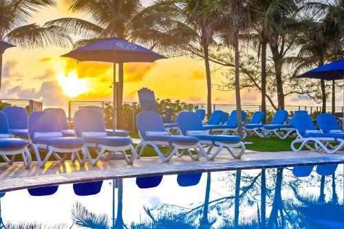 a group of chairs and umbrellas next to a pool at Luxury Penthouse Oasis - Oceanfront Views & Resort Perks in Sunny Isles Beach