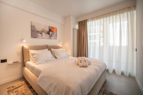 Un dormitorio con una cama con sábanas blancas y una ventana. en Lotus Apartment 140 in Odyssey Pool & Spa-parking, en Mamaia