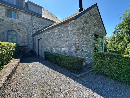 a stone building with bushes next to a building at Les Gîtes du Château de Bellaire in Gesves