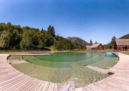 une grande piscine d'eau avec une maison en arrière-plan dans l'établissement Le Dôme Alpin pied des Pistes, à Saint-Chaffrey