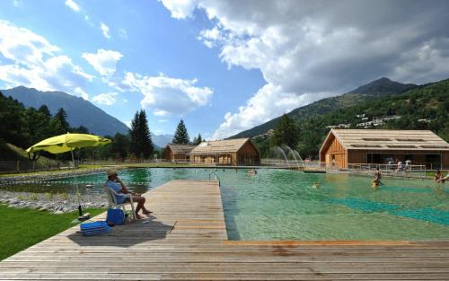 une personne assise dans une chaise à côté d'une piscine dans l'établissement Le Dôme Alpin pied des Pistes, à Saint-Chaffrey