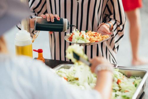 une personne préparant de la nourriture dans une cuisine avec un plateau de nourriture dans l'établissement Family surfcamp Messanges, à Messanges