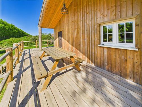 a wooden deck with a picnic table on the side of a building at Le Pti Prins in Hatrival