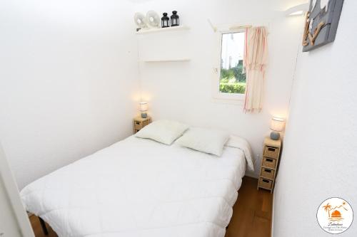 une petite chambre avec un lit blanc et une fenêtre dans l'établissement St cyprien superbe appart 4 pers vue sur la marina, à Saint-Cyprien