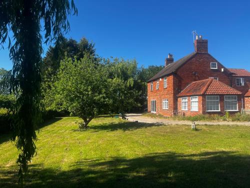 an old brick house with a tree in front of it at Wellbet Farm in Swinderby