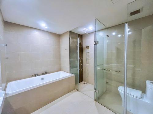 a bathroom with a tub and a glass shower at Monica Homestay - Căn hộ The Song Vũng Tàu in Vung Tau