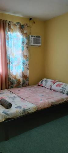 a bedroom with a bed with a window and an air conditioner at Affordable Whole House Rent Transient in Butuan