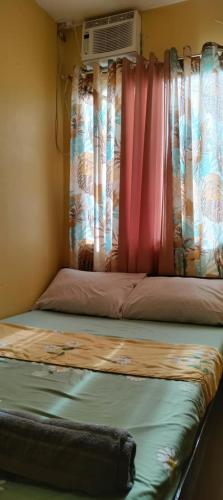a bed in a room with a window with a fan at Affordable Whole House Rent Transient in Butuan
