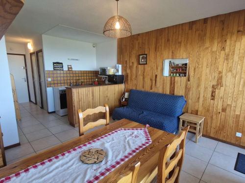 un salon avec un canapé bleu et une table dans l'établissement Studio Chaleureux 4 Pers avec Terrasse - Saint-Michel-de-Chaillol - FR-1-393-52, à Saint-Michel-de-Chaillol