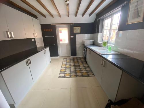 a kitchen with white cabinets and a tile floor at Wellbet Farm in Swinderby