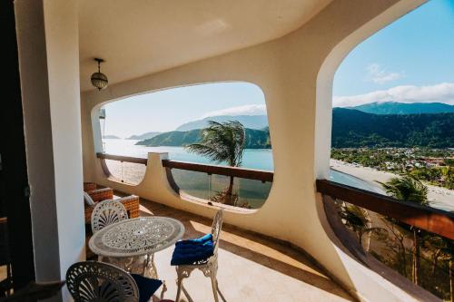 a room with a balcony with a view of the ocean at Conforto, Vista linda e Pé na Areia | Barequeçaba in São Sebastião
