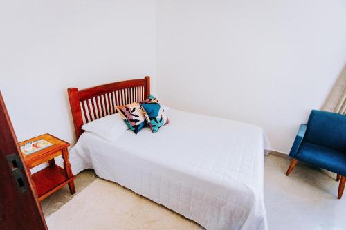 a bedroom with a white bed and a blue chair at Conforto, Vista linda e Pé na Areia | Barequeçaba in São Sebastião