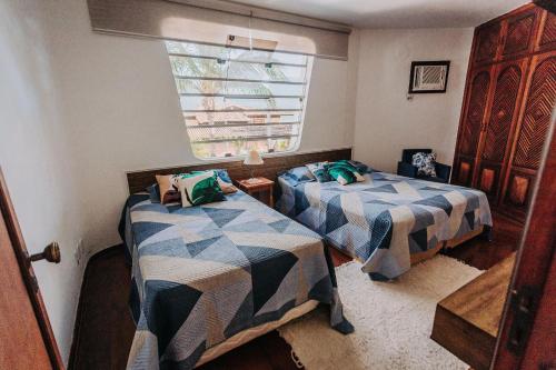 a bedroom with two beds and a window at Conforto, Vista linda e Pé na Areia | Barequeçaba in São Sebastião
