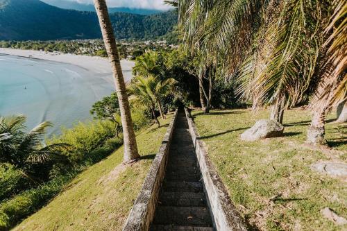 a set of stairs next to a beach with palm trees at Conforto, Vista linda e Pé na Areia | Barequeçaba in São Sebastião