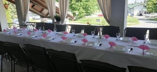 a long white table with pink napkins and glasses at Šulentić sobe i restoran in Virovitica