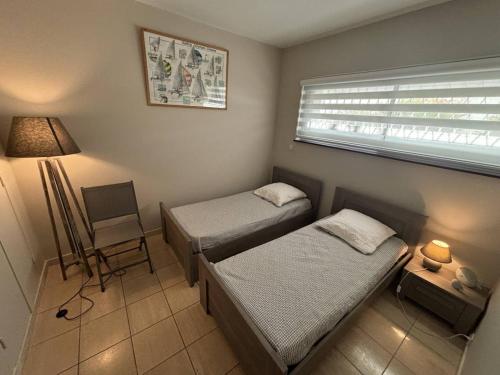 une chambre avec deux lits et une lampe et une fenêtre dans l'établissement Appartement 3P en RDJ avec Jardin et Terrasse, à 5 min Plage et Restaurants, Parking Privé, Climatisé - FR-1-252A-59, à Villeneuve-Loubet