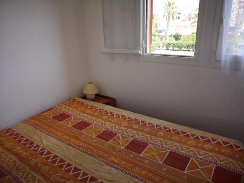 un lit dans une chambre avec une fenêtre dans l'établissement Appartement T2 Cabine - 6 pers, Parking - Le Barcarès - FR-1-195-83, au Barcarès