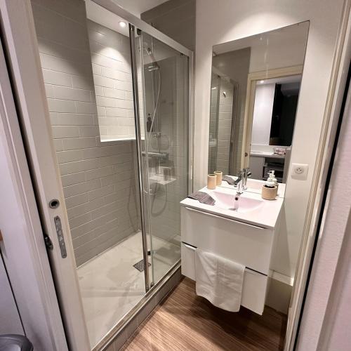une salle de bain blanche avec une douche et un lavabo dans l'établissement Tourny Bordeaux Studio, à Bordeaux