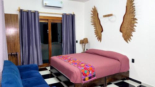 a bedroom with a bed and a blue couch at Casa Jabalí Ecocchic in Tulum