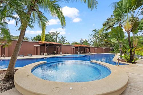 a swimming pool with palm trees in front of a building at Langosta Beach Ocean View Penthouse w Pool in Tamarindo