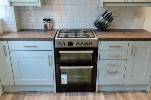 a kitchen with a stove and white cabinets at Modern Double Room with Broadband, Private TV in Shared House - Room 5 in Solihull