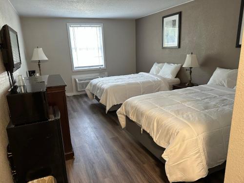 a hotel room with two beds and a flat screen tv at Whalers Inn and Suites in New Bedford