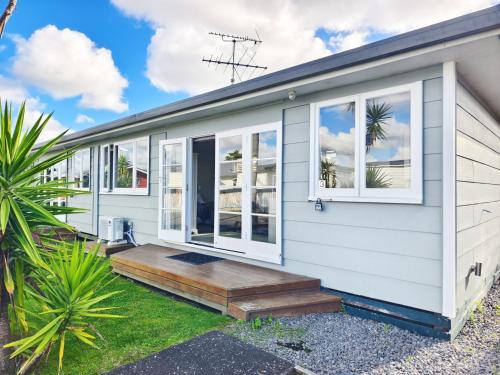 a manufactured home with a wooden porch and windows at Parakai Geothermal Motel in Parakai