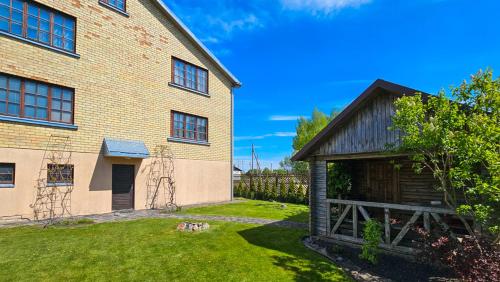 a brick house with a yard next to a building at Guest house Sunrise in Šiauliai