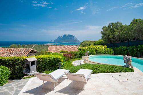 a house with a swimming pool and two lounge chairs at Villa Kiki - Klodge in Costa Corallina