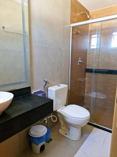 a bathroom with a toilet and a glass shower at Pousada Mariluz in Maragogi