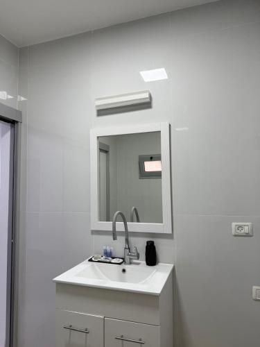 un bagno bianco con lavandino e specchio di בוטיק המשי a Beit She'an