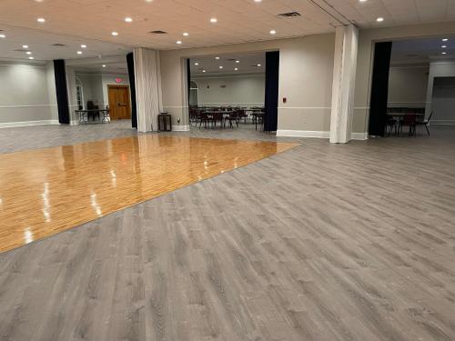 a ballroom with a wooden floor and tables and chairs at Whalers Inn and Suites in New Bedford