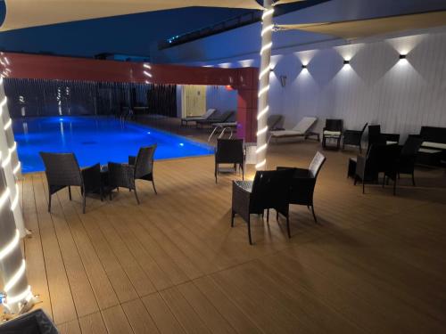 a swimming pool with chairs and a table in front of it at Carnelian Muscat - Airport Hotel in Muscat