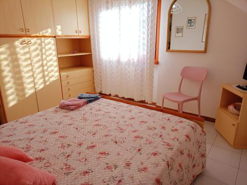 a bedroom with a bed and a chair and a window at Carmen House in Grottammare