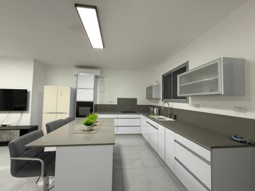 a kitchen with white cabinets and a table and chairs at בוטיק המשי in Bet Sheʼan