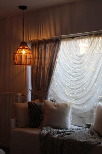 a window with a curtain and a lamp and a couch at Casa Lucia in Dămuc