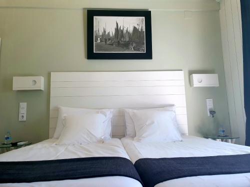 a bed with white sheets and a picture on the wall at Hostal Mi Campaña in Denia