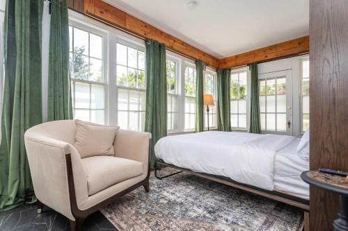 a bedroom with a bed and a chair and windows at First Floor Suites at The Legacy Inn Harmony Floor in Luray