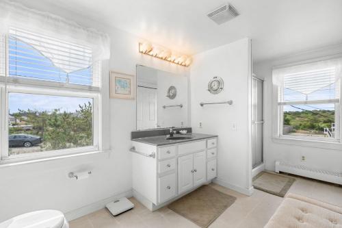 Baño blanco con lavabo, bañera y ventanas en 283 Phillips Road Sagamore Beach - Cape Cod, en Sagamore Beach