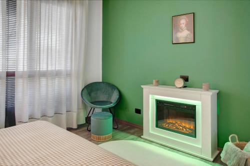 a green bedroom with a fireplace and a chair at Il Rifugio di Sebi in Morbegno
