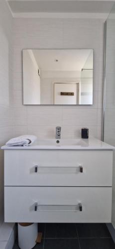 une salle de bain blanche avec un lavabo et un miroir dans l'établissement Charmant T2 au calme avec vue mer, proche centre de Collioure et parking, à Collioure