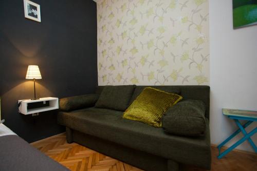 a living room with a green couch with a yellow pillow at Villa Makarana Apartments in Makarska