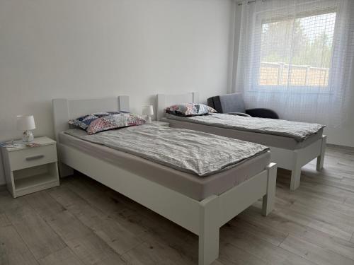 Dos camas individuales en una habitación con ventana. en LG Apartman Siófok, en Siófok