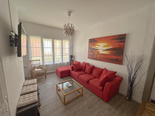 een woonkamer met een rode bank en een tafel bij Villa familiale proche Océan in Soulac-sur-Mer