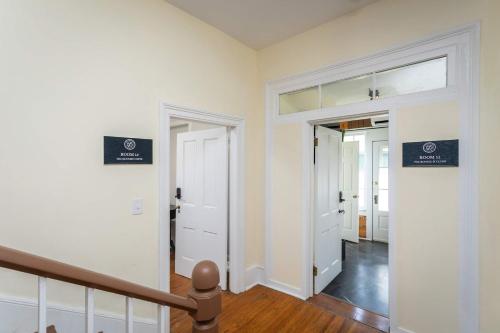 a hallway with white walls and a staircase with two doors at The Legacy Suites Collection Full Property Rental in Luray