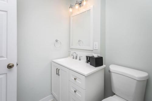 a white bathroom with a sink and a mirror at The Legacy Suites Collection Full Property Rental in Luray