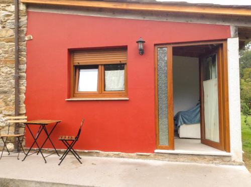 a red tiny house with a table and a bed at Apartamentos PENAQUENTE in Porto de Espasante